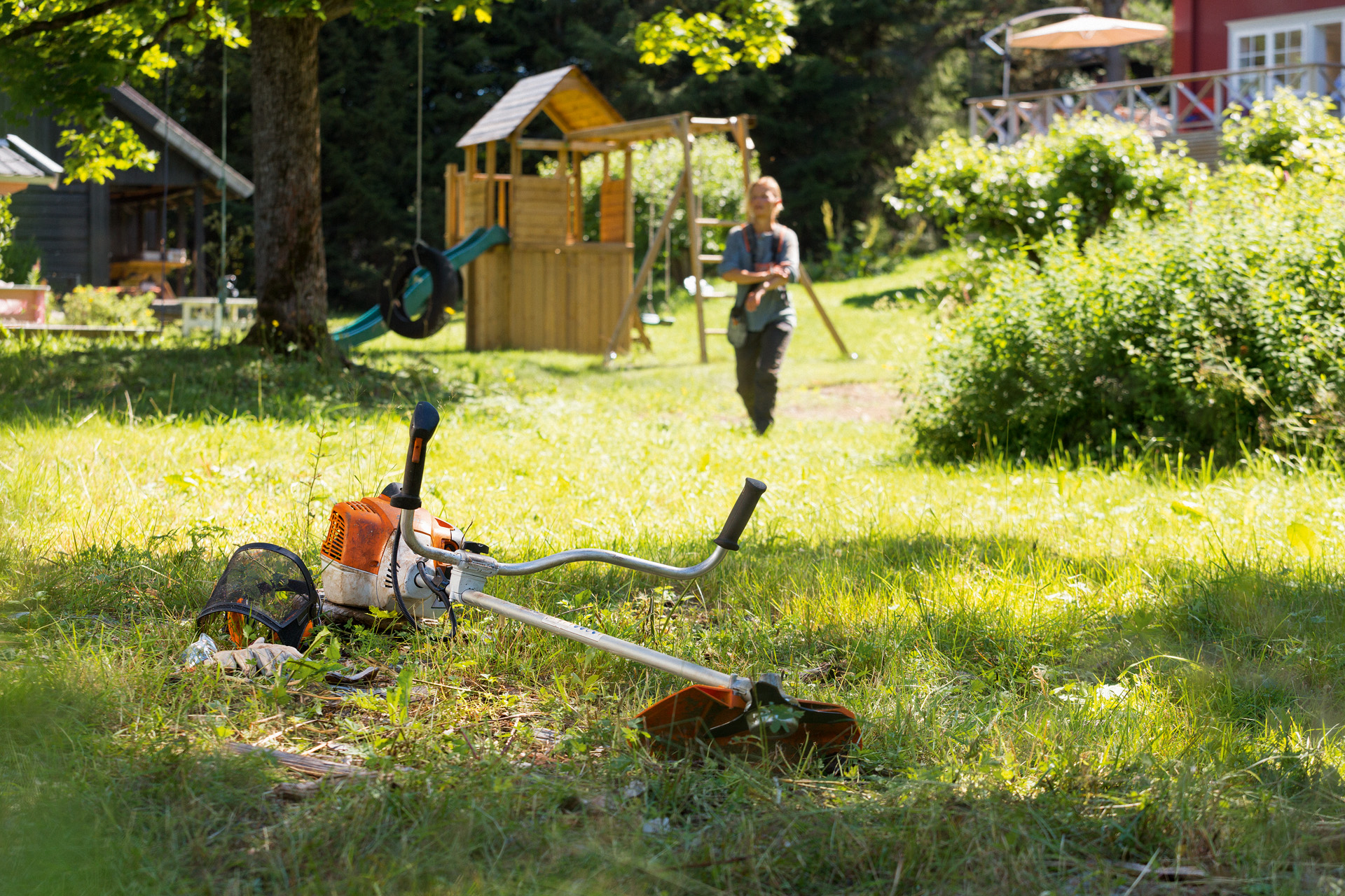 Una motoguadaña STIHL FS 240 sobre la hierba, en segundo plano un hombre se prepara para el mantenimiento