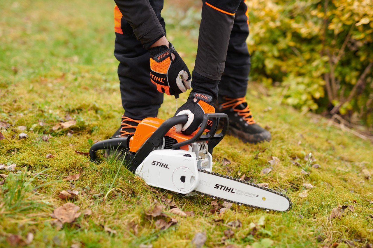 Bidón de mezcla para STIHL MotoMix, aceite y gasolina y una motosierra de gasolina STIHL MS 261 C en un taller