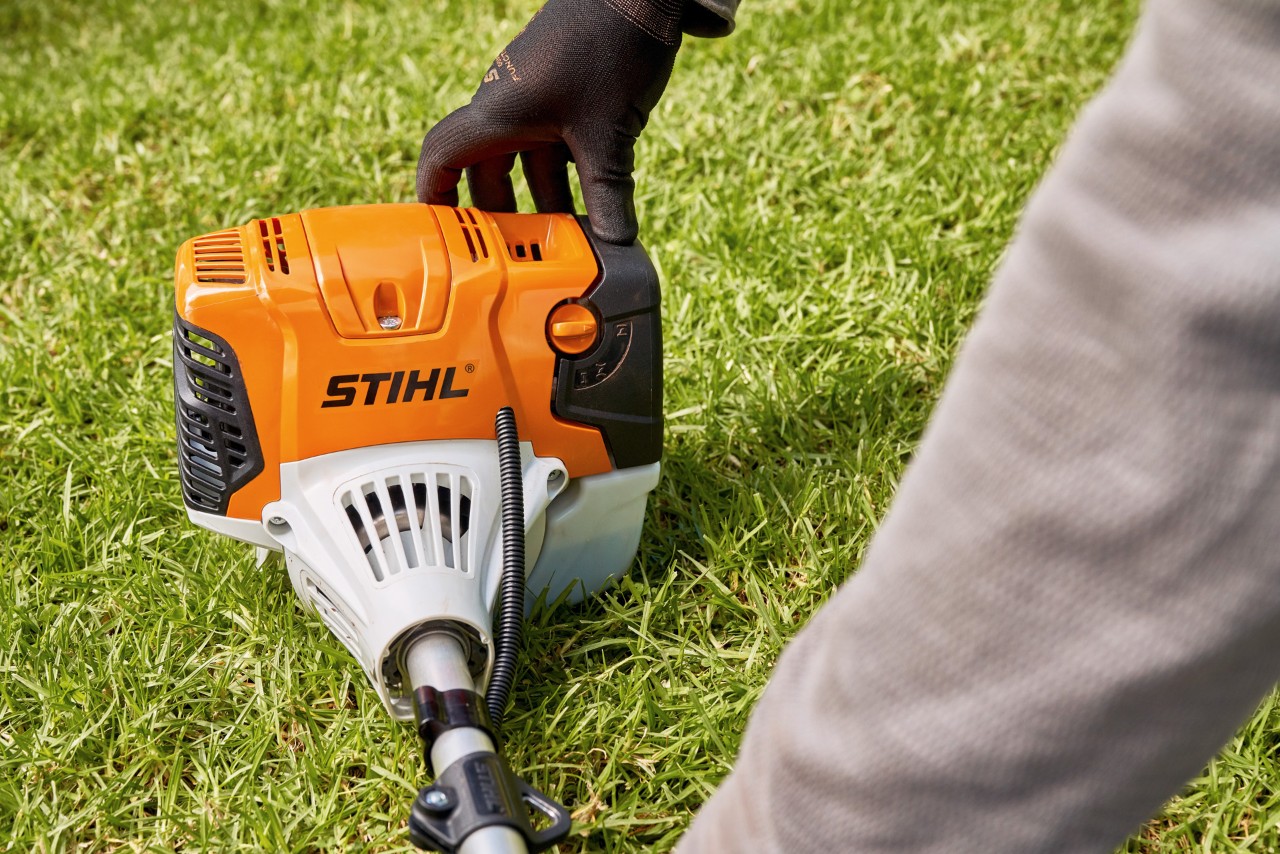 Un hombre presiona la desbrozadora de gasolina STIHL FS 91 firmemente contra el suelo