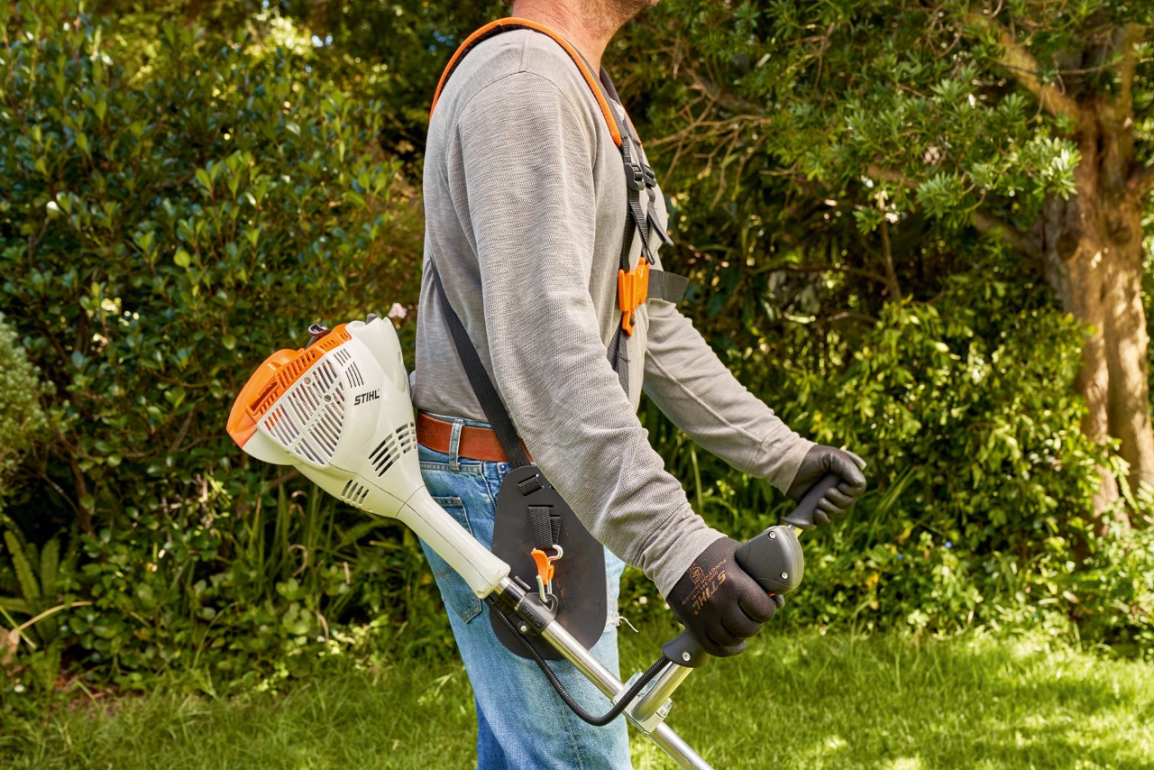 Un hombre levanta la desbrozadora de gasolina STIHL FS 56 del suelo