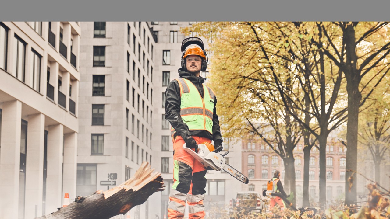 Un hombre con una motosierra STIHL delante de un árbol