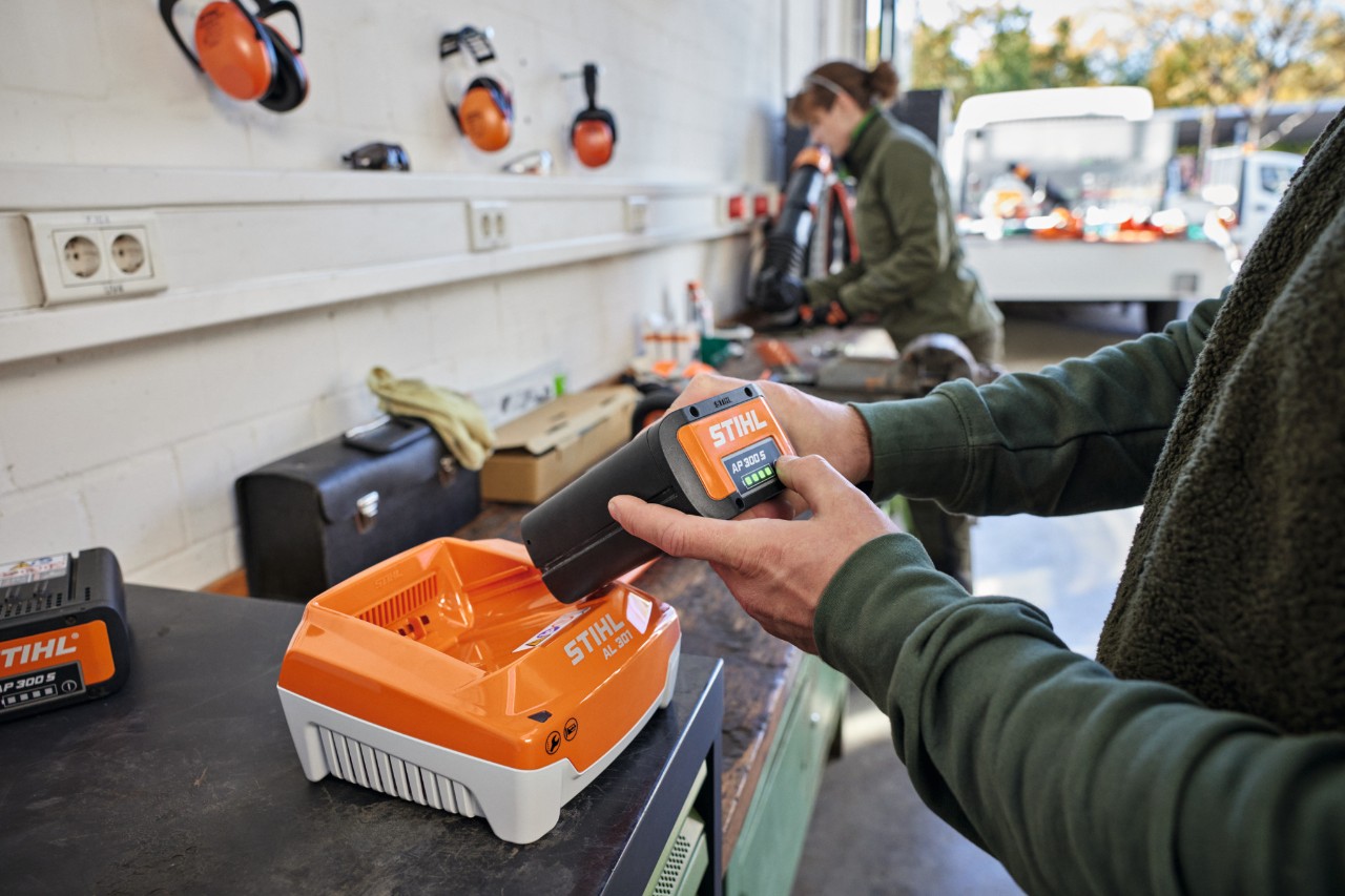 Una persona inserta una batería STIHL AP 300 S en un cargador rápido STIHL AL 301